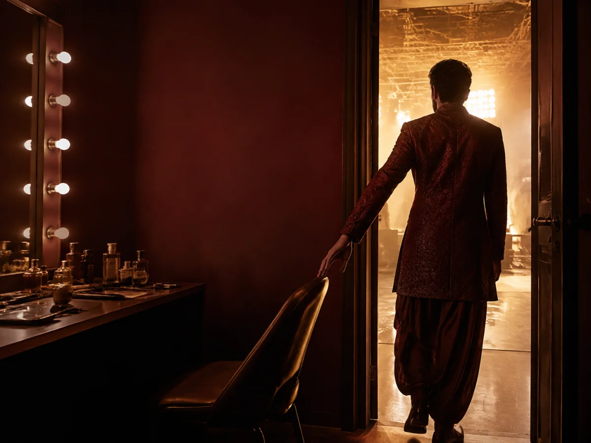 An Indian performer leaving a dressing room and stepping onto a bright set